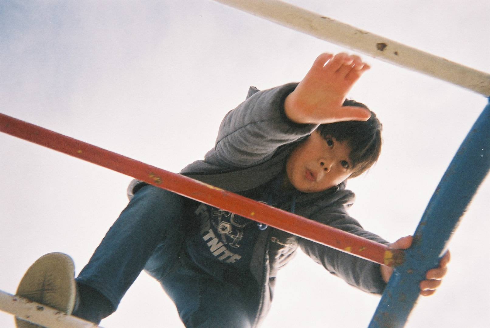 a kid climbing a playground structure, shot from below