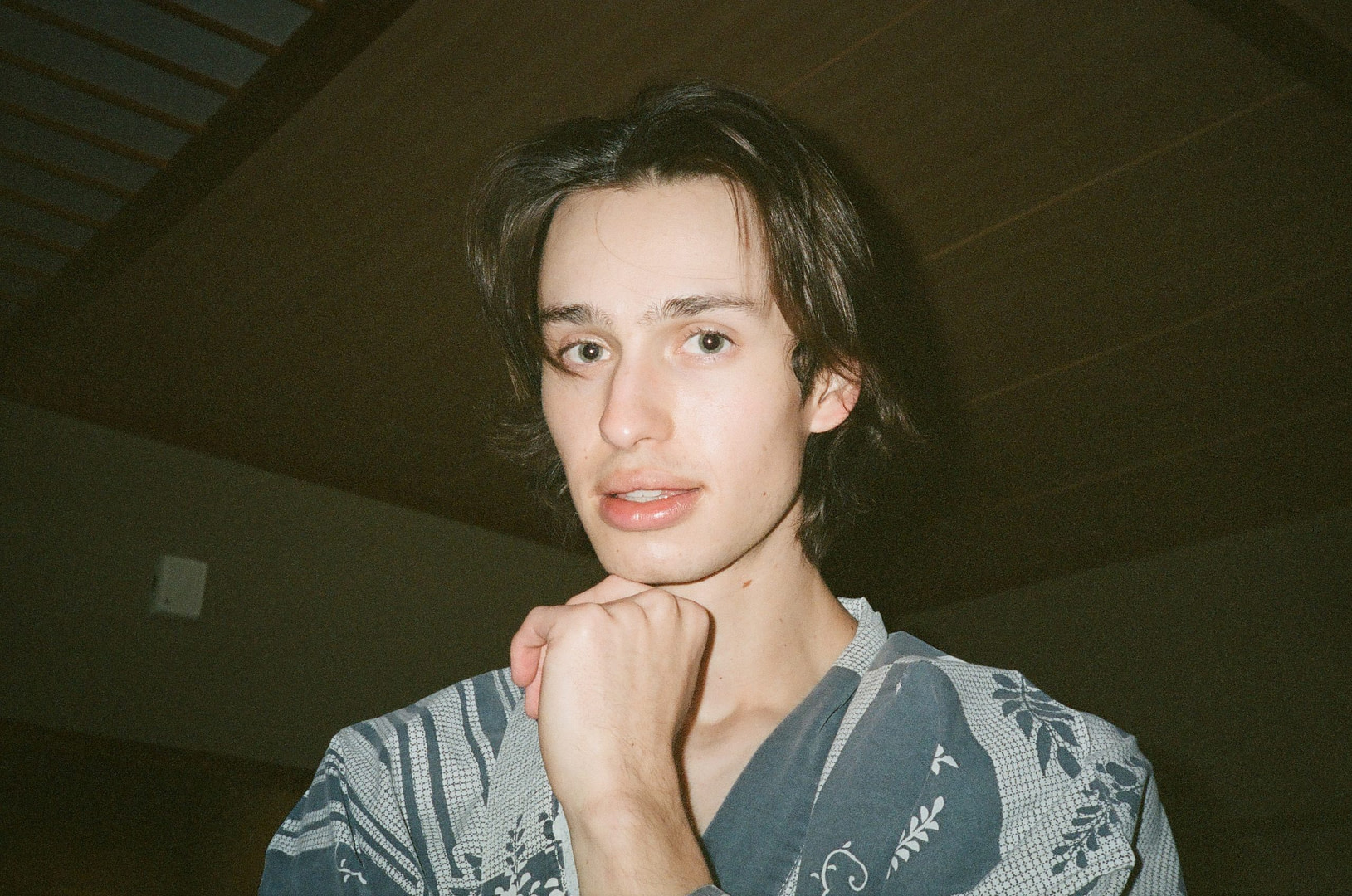 a boy looking at the camera with his hand to his chin in a thinking pose, wearing traditional japanese clothing