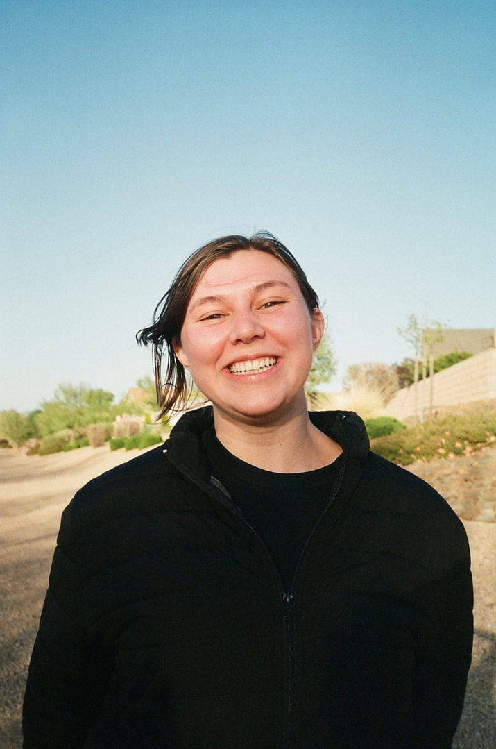 a girl smiling to the camera in a sunny neighborhood in the desert
